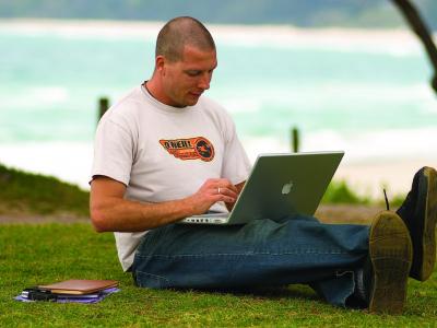Student using his laptop at the beach! Photo credit: North Coast Institute of TAFE